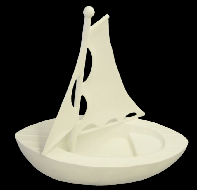 White fiberglass sailboat sculpture with a rounded hull and upright sail featuring cut-out holes, viewed from an angle.