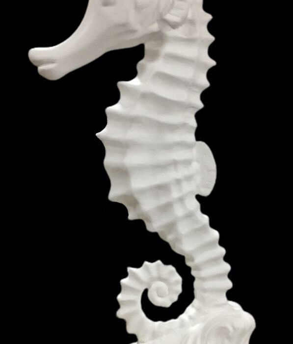 Side view of a white fiberglass seahorse sculpture with a curled tail.